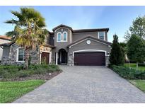 Elegant two-story home featuring stone accents, a well-manicured lawn, and a spacious driveway leading to a two-car garage at 8405 Adalina Pl, Orlando, FL 32827