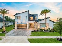 Modern two-story home with a glass-door garage, manicured lawn, and a beautiful brick driveway at 9877 Laurel Berry Dr, Orlando, FL 32827