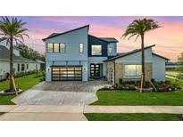 Modern two-story home with a striking architectural design, well-manicured lawn, and a stylish black-framed glass garage door at 9877 Laurel Berry Dr, Orlando, FL 32827