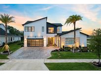 Modern two-story home featuring a glass garage door, lush landscaping and an eye-catching elevated roofline at 9877 Laurel Berry Dr, Orlando, FL 32827