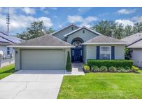 Charming home with a manicured lawn, a two-car garage, and a stylish front door with an arched window above at 9931 Cypress Knee Cir, Orlando, FL 32825