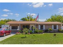 Charming single-story home featuring a lush lawn, lovely garden beds, and an American flag at 1219 Blue Spring Ct, Ocoee, FL 34761