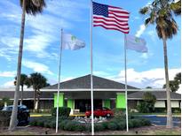 Welcoming building entrance featuring flags, lush landscaping, and convenient parking at 5245 W Irlo Bronson Memorial Hwy # 151, Kissimmee, FL 34746