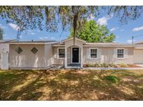 Inviting single-story home with black door, white shutters and shade trees in the front yard at 1084 Doyle Rd, Deltona, FL 32725