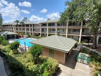 A view of the in-ground community pool area with lush landscaping, and seating areas, surrounded by condos at 131 Water Front Way # 200, Altamonte Springs, FL 32701