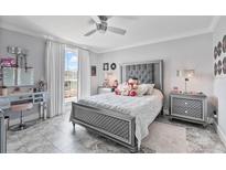 Cozy bedroom features gray walls, tile floor, and plush bedding with a ceiling fan, natural light, and a vanity at 1450 Belfiore Way, Windermere, FL 34786