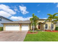 Charming single-Gathering home featuring a three-car garage, landscaped yard, and tropical palm trees at 16313 Birchwood Way, Orlando, FL 32828