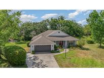 Charming single-story home featuring a well-maintained lawn, lush landscaping, and a two-car attached garage at 5494 Glen Oak Pl, Sanford, FL 32771