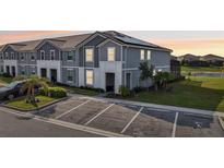 Two-story townhome featuring a gray exterior, solar panels, landscaping, and convenient parking spaces at 7554 Oak Spring Ln, Davenport, FL 33837