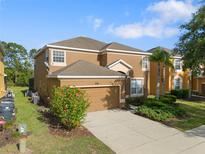 Two-story home boasts a well-manicured lawn, mature landscaping, and an attached two-car garage at 957 Orange Cosmos Blvd, Davenport, FL 33837