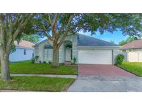 Charming single-story home with a brick driveway, mature trees, and a well-maintained lawn at 13434 Mallard Cove Blvd, Orlando, FL 32837