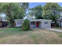 Charming single-story home with a well-maintained lawn, mature trees and newly painted gray exterior at 136 Country Club Dr, Sanford, FL 32771
