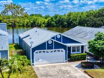 Charming blue home boasts a well-maintained lawn, attached garage and lovely lake view at 148 Meadow Blvd, Sanford, FL 32771
