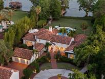 Stunning aerial view of a luxury home with a terracotta roof, manicured landscaping, and a pool overlooking the waterfront at 1640 E Adams Dr, Maitland, FL 32751