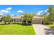 Charming single-story home with a well-manicured lawn, lovely landscaping, and a brick-paved driveway at 18108 Bellezza Dr, Orlando, FL 32820