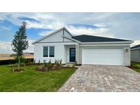 Charming single-story home with a two-car garage, brick driveway, and fresh landscaping at 2013 Stone Wall Ct, Lake Hamilton, FL 33851