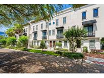 Charming townhome showcases a white facade, manicured landscaping, and a welcoming brick-paved street at 220 S Summerlin Ave, Orlando, FL 32801