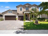 Charming two-story home featuring a three-car garage, landscaped yard, and a paver driveway under a sunny sky at 2614 Mead Ave, St Cloud, FL 34771