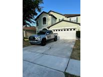Two story home with front garage, well-manicured lawn, and truck in the driveway at 2806 Polson Dr, Kissimmee, FL 34758