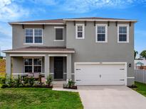 Charming two-story home featuring a well-maintained lawn, covered porch with bench, and a two-car garage at 3033 Beau Loop, Tavares, FL 32778