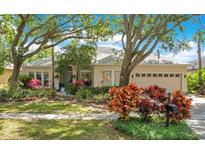 Charming single-story home featuring a well-maintained lawn, mature trees, and colorful landscaping at 4219 Lillian Hall Ln, Orlando, FL 32812