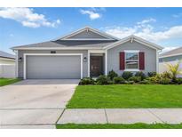 Charming single-story home with a well-manicured lawn, attached garage, and red accent shutters at 5347 Travertine St, Mount Dora, FL 32757