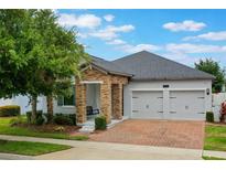 Charming home features a two-car garage, beautiful brick paved driveway, and inviting stone columns on the covered porch at 7605 Lake Hancock Blvd, Winter Garden, FL 34787