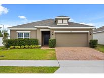 Charming single-story home featuring a well-maintained lawn, neat landscaping, and a brick-paved driveway at 849 Avenal Ln, Davenport, FL 33837