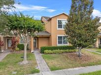 Inviting two-story townhome with a well-manicured lawn, mature trees, and a cozy entrance at 9009 Savannah Julip Ln, Orlando, FL 32832
