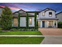 Beautiful two-story home with a brick driveway, manicured lawn, and vibrant landscaping offering excellent curb appeal at 10139 Austrina Oak Loop, Winter Garden, FL 34787