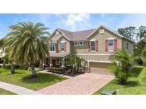 Charming two-story home with a brick driveway, beautiful landscaping, and a large palm tree at 15242 Heron Hideaway Cir, Winter Garden, FL 34787