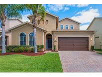 Charming home featuring a paver driveway, two-car garage and lush landscaping with palm trees at 15443 Sugarcup Ct, Orlando, FL 32828