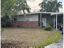 Single-story home featuring a carport, neutral color palette, brick accents, and a spacious front yard at 1909 Edwin Blvd, Winter Park, FL 32792
