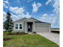 Beautiful one-story home with gray stucco, manicured lawn, and paver driveway to a two car garage at 2009 Stone Wall Ct, Lake Hamilton, FL 33851