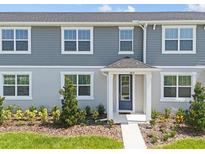 Charming townhouse with a blue front door, well-maintained landscaping, and gray siding at 2831 Camellia Flower St, Apopka, FL 32703