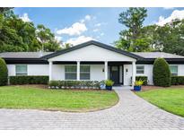 Charming single-story home with white siding, black trim, manicured landscaping, and a welcoming entryway at 3011 Temple Trl, Winter Park, FL 32789