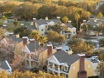 Beautiful aerial view showcasing yellow condos, lush greenery, and palm trees, near a golf course at 7518 Seven Eagles Way # 201, Reunion, FL 34747