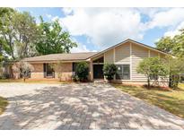 Charming single-story home with brick and siding, surrounded by mature trees and a brick driveway at 100 Crestwood Dr, Longwood, FL 32779