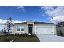 Charming single-Gathering home with a two-car garage, blue entry door, and beautifully landscaped front yard at 1012 Bear Hammock Dr, Umatilla, FL 32784