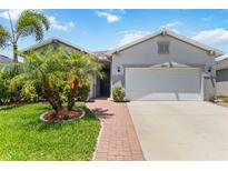 Charming single-Gathering home features lush landscaping, a brick walkway, and a two-car garage at 12335 Sumter Dr, Orlando, FL 32824