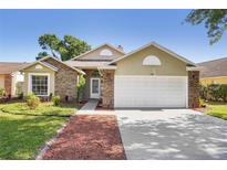 Charming single-Gathering home featuring a two-car garage, brick accents, and a well-maintained lawn at 143 Abbey Hollow Dr, Apopka, FL 32712