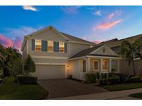 Charming two-story home with a manicured lawn and inviting brick driveway at dusk at 14742 Bahama Swallow Blvd, Winter Garden, FL 34787