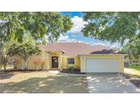 Inviting one-story home with a two-car garage, mature trees, and a well-manicured front yard at 1512 Adriatic Dr, Ocoee, FL 34761