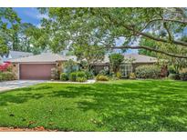 Charming single-story home featuring a manicured lawn, mature trees, and a stone-accented facade, with a two-car garage at 3960 Lake Mira Dr Dr, Orlando, FL 32817