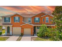 Inviting townhome with a two car garage, blue shutters, and warm orange exterior paint at 5118 Adelaide Dr, Kissimmee, FL 34746