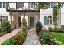 Charming home exterior with beautiful landscaping and inviting front entrance with arched door and paver walkway at 8848 Bismarck Palm Dr, Winter Garden, FL 34787
