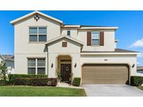 Charming two-story home featuring a well-manicured lawn, complemented by a two-car garage and neutral color palette at 889 Boxelder Ave, Minneola, FL 34715