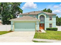 Inviting two-story home with a two-car garage, well-manicured lawn, and beautiful landscaping at 905 Cascade Falls Ln, Deland, FL 32720