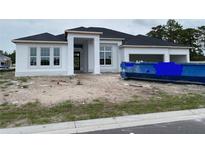 Under construction exterior of a white home with a three-car garage and large windows on a cloudy day at 960 Hawksnest Pt, Oviedo, FL 32765