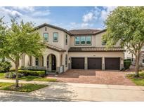 Stunning two-story home featuring a three-car garage and a brick paved driveway at 9574 Meadow Hunt Way, Winter Garden, FL 34787